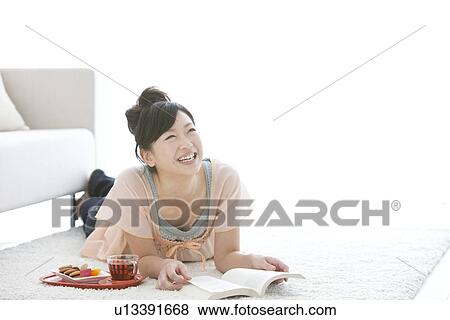 Young woman lying on front and reading a book View Large Photo Image Stock Photo - Young woman lying on front and reading a book. Fotosearch