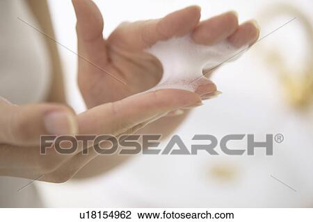 Stock Image - Young woman making soap suds with hands, close up. Fotosearch