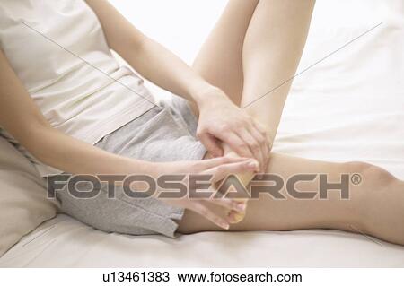 Young woman massaging foot on bed View Large Photo Image Stock Image - Young woman massaging foot on bed. Fotosearch