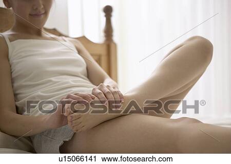 Young woman massaging foot on bed View Large Photo Image Stock Image - Young woman massaging foot on bed. Fotosearch