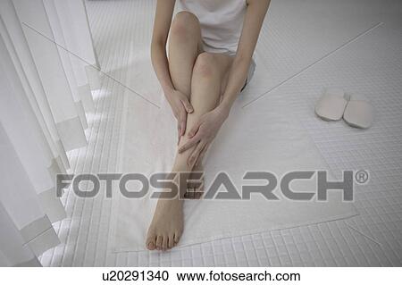 Young woman massaging legs in bathroom View Large Photo Image Stock Image - Young woman massaging legs in bathroom. Fotosearch