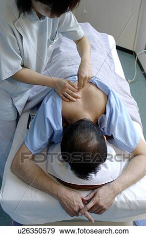 Stock Photo - Young woman placing moxa on man's back. Fotosearch
