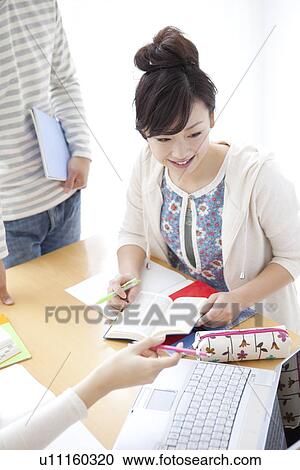 Stock Image - Young woman pointing at laptop. Fotosearch