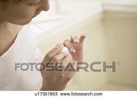 Stock Image - Young woman polishing nails, close up. Fotosearch
