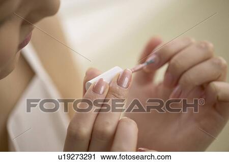 Stock Image - Young woman polishing nails, close up. Fotosearch