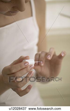 Stock Photo - Young woman polishing nails. Fotosearch