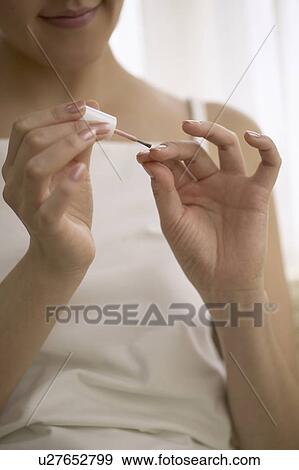 Stock Photo - Young woman polishing nails. Fotosearch