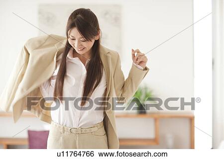 Young woman putting on jacket, smiling View Large Photo Image Stock Photograph - Young woman putting on jacket, smiling. Fotosearch