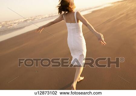 Stock Image - Young woman running on beach. Fotosearch