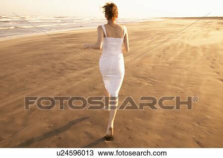 Stock Image - Young woman running on beach. Fotosearch