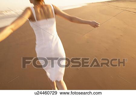 Stock Photo - Young woman running on beach. Fotosearch