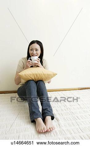 Young woman sitting and holding cushion View Large Photo Image Stock Image - Young woman sitting and holding cushion. Fotosearch