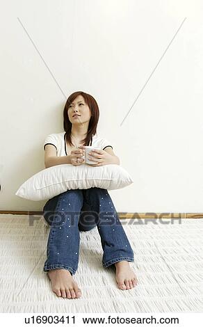 Young woman sitting and holding cushion View Large Photo Image Stock Image - Young woman sitting and holding cushion. Fotosearch