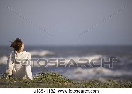 Young woman sitting on beach View Large Photo Image Stock Image - Young woman sitting on beach. Fotosearch