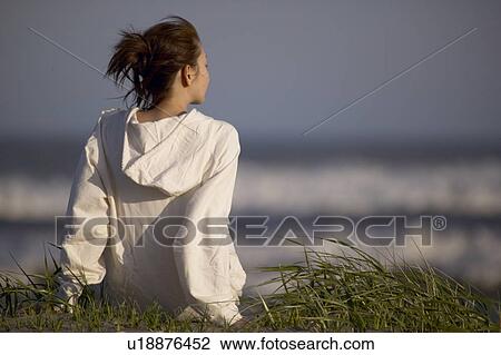 Young woman sitting on beach View Large Photo Image Stock Image - Young woman sitting on beach. Fotosearch