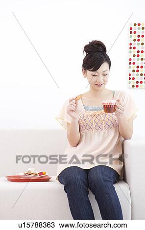Young woman sitting on couch drinking tea View Large Photo Image Stock Image - Young woman sitting on couch drinking tea. Fotosearch