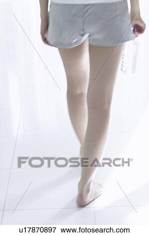 Young woman standing by window, holding bottle of water View Large Photo Image Stock Photo - Young woman standing by window, holding bottle of water. Fotosearch