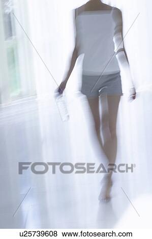 Young woman standing by window, holding bottle of water, soft focus, blurred motion View Large Photo Image Stock Photo - Young woman standing by window, holding bottle of water, soft focus, blurred motion. Fotosearch