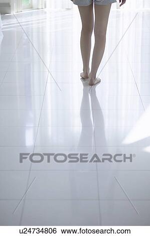 Stock Photograph - Young woman standing by window. Fotosearch
