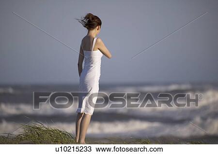 Stock Image - Young woman standing on beach. Fotosearch