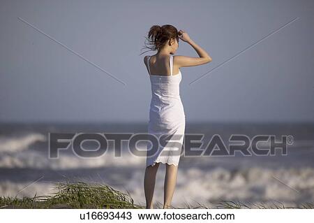 Young woman standing on beach View Large Photo Image Stock Image - Young woman standing on beach. Fotosearch