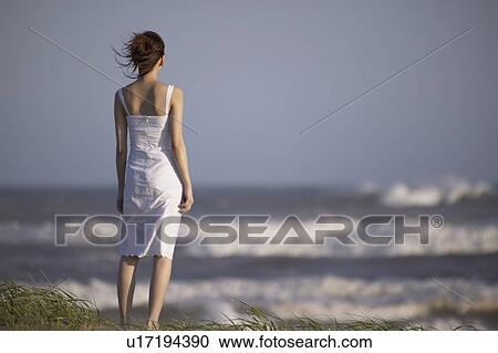 Young woman standing on beach View Large Photo Image Stock Image - Young woman standing on beach. Fotosearch