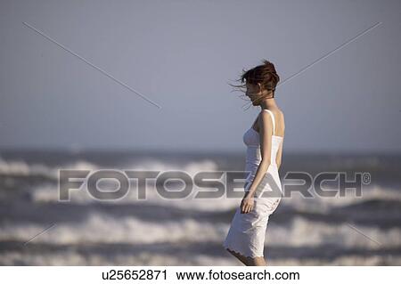 Stock Image - Young woman standing on beach. Fotosearch