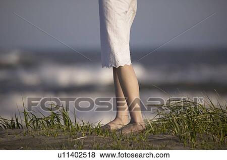 Young woman standing on beach View Large Photo Image Stock Photo - Young woman standing on beach. Fotosearch