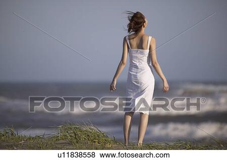 Stock Photo - Young woman standing on beach. Fotosearch