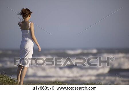 Young woman standing on beach View Large Photo Image Stock Photograph - Young woman standing on beach. Fotosearch