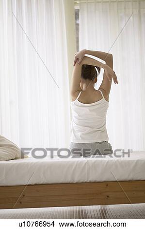Young woman stretching on bed View Large Photo Image Picture - Young woman stretching on bed. Fotosearch