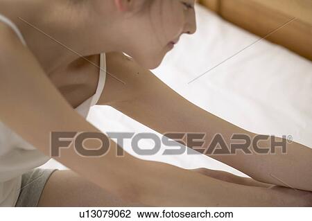 Stock Image - Young woman stretching on bed. Fotosearch
