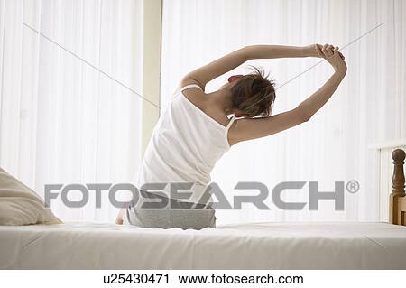 Young woman stretching on bed View Large Photo Image Stock Image - Young woman stretching on bed. Fotosearch