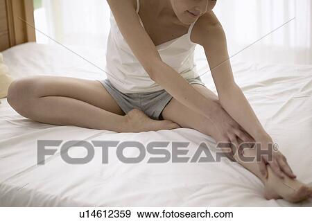 Stock Photo - Young woman stretching on bed. Fotosearch