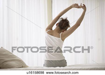 Stock Photo - Young woman stretching on bed. Fotosearch