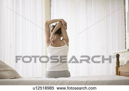 Stock Photography - Young woman stretching on bed. Fotosearch