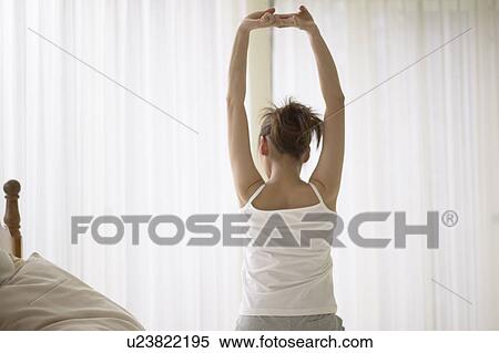 Stock Photography - Young woman stretching on bed. Fotosearch