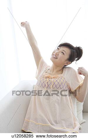 Young woman stretching on couch View Large Photo Image Stock Photography - Young woman stretching on couch. Fotosearch
