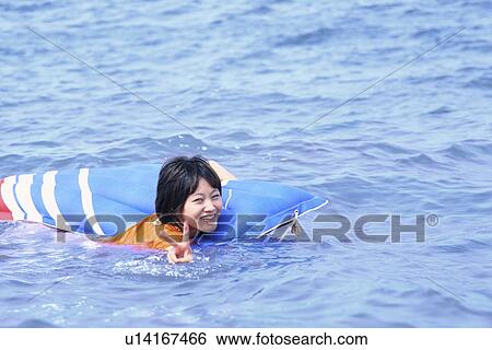Stock Photograph - Young woman swimming at sea, Toyama Prefecture, Honshu, Japan. Fotosearch