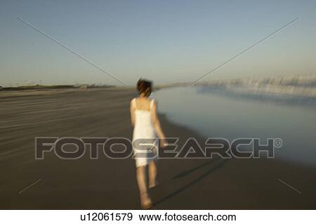 Stock Photo - Young woman walking on beach, blurred motion. Fotosearch