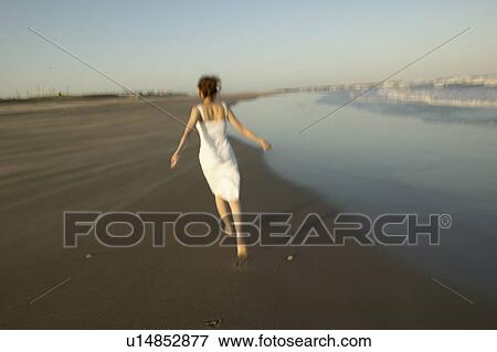 Young woman walking on beach, blurred motion View Large Photo Image Stock Photo - Young woman walking on beach, blurred motion. Fotosearch