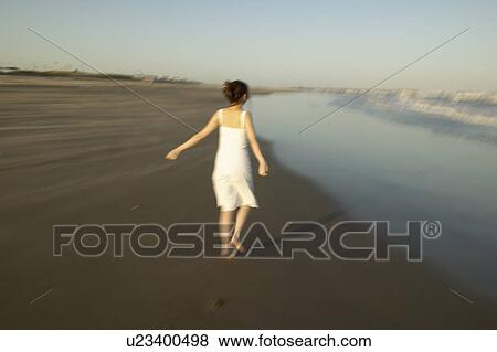 Stock Photo - Young woman walking on beach, blurred motion. Fotosearch