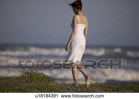 Stock Image - Young woman walking on beach. Fotosearch
