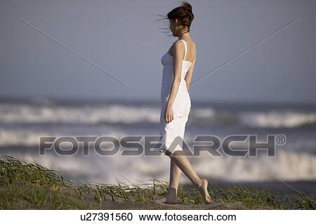 Stock Image - Young woman walking on beach. Fotosearch