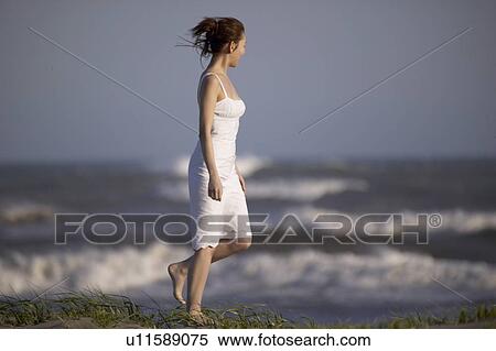 Stock Photography - Young woman walking on beach. Fotosearch