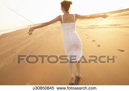 Stock Photography - Young woman walking on beach. Fotosearch