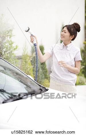Young woman washing car, holding hose View Large Photo Image Stock Image - Young woman washing car, holding hose. Fotosearch