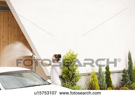 Young woman washing car, holding hose View Large Photo Image Stock Photo - Young woman washing car, holding hose. Fotosearch