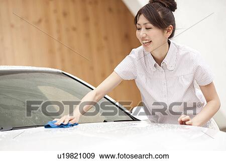 Stock Photo - Young woman washing car, smiling. Fotosearch