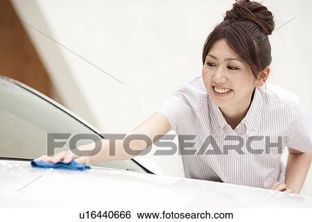Stock Photograph - Young woman washing car, smiling. Fotosearch